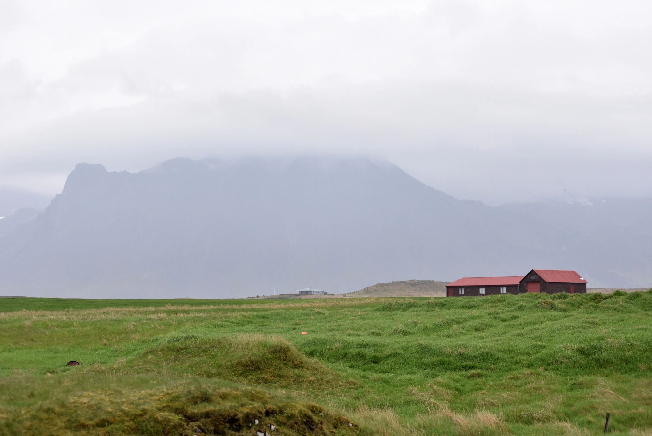 Farmhouses beneath misty mountains in a quiet rural landscape